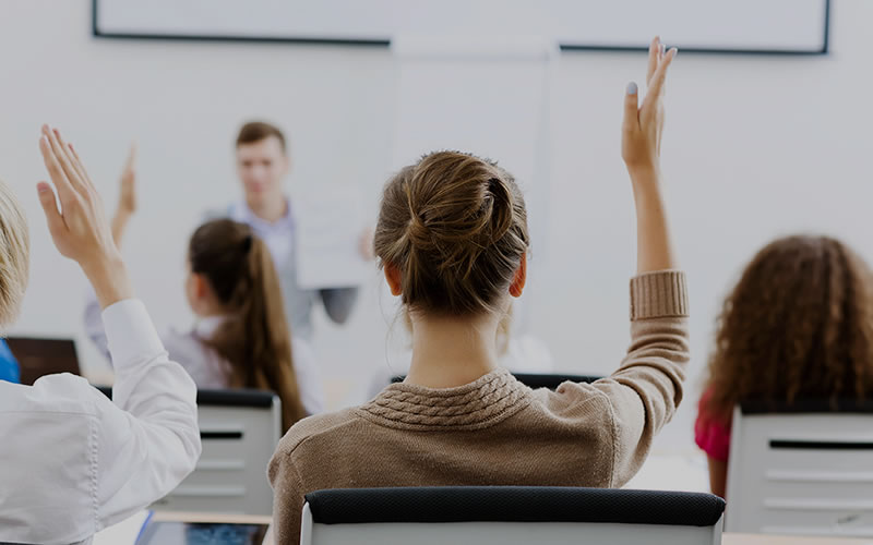 Woman raising her arm to answer a question regarding first aid